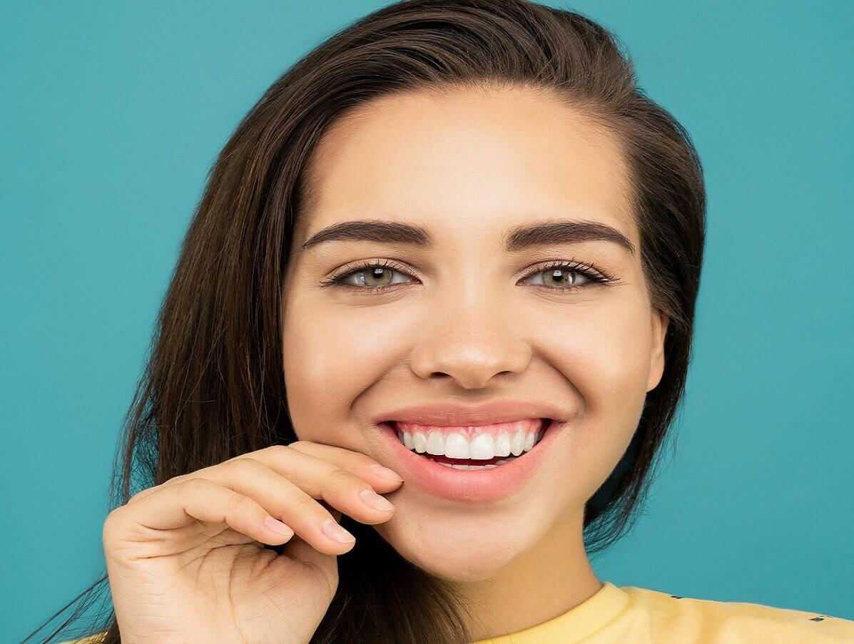 woman in yellow shirt smiling with perfect straight teeth