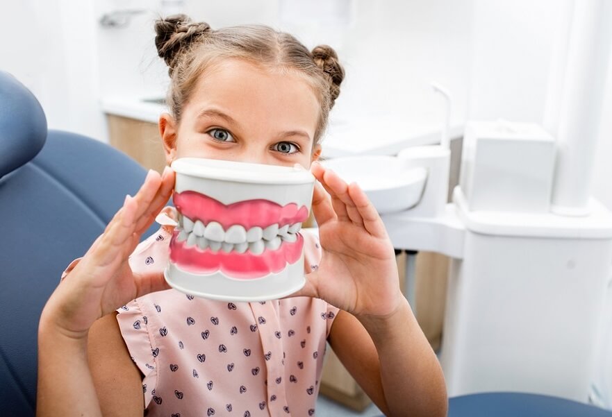 Macquarie Dentists - kid plying with fake teeth at dentist office
