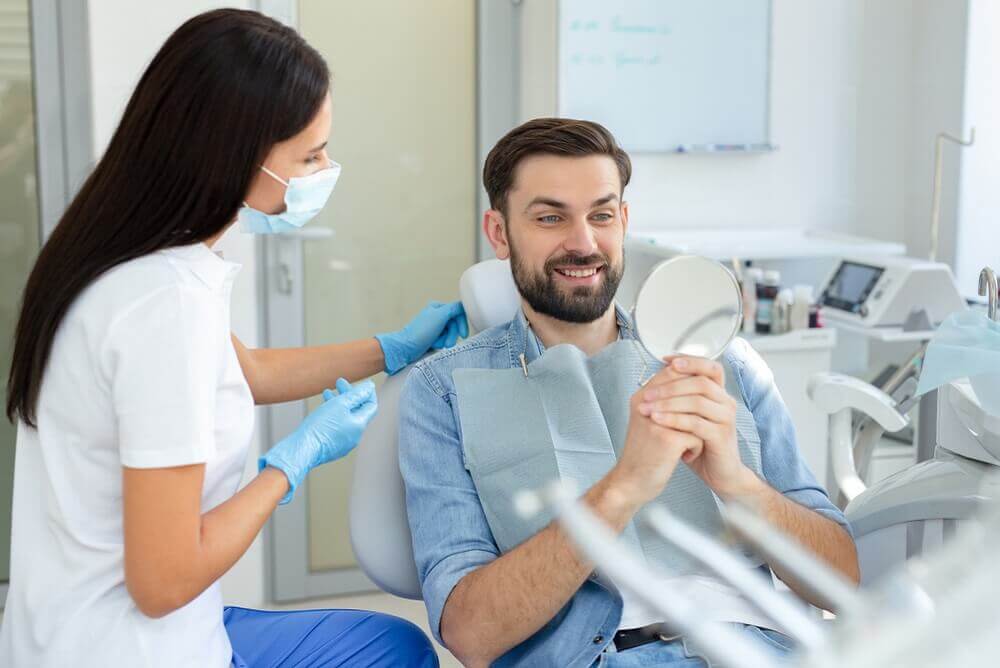 Macquarie Dentists - patient smiling on mirror checking his Invisalign