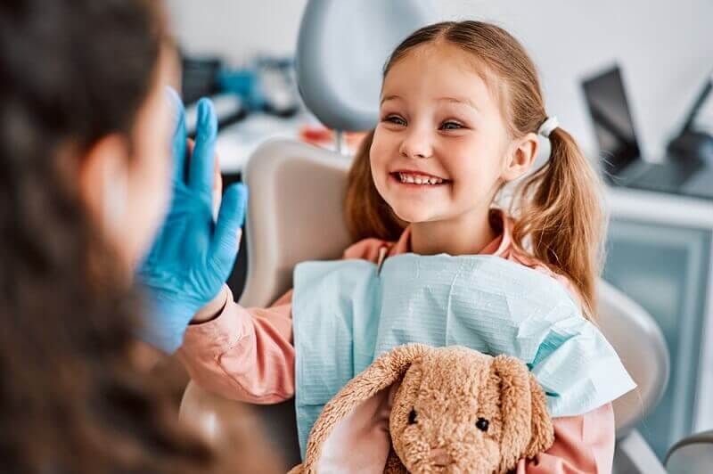 Macquarie Dentists - a child sitting on a dental chair smiling to her dentist