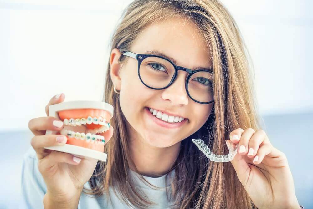 Macquarie Dentists - woman holding metal braces and Invisalign
